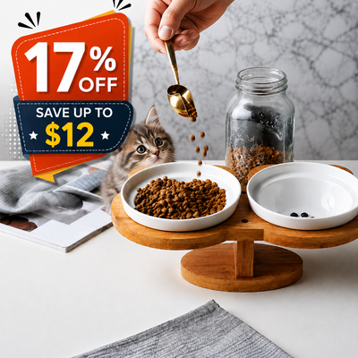 A wooden pet feeder stand with two white bowls, shown with dry cat food in one bowl, a cat peeking from behind, and a hand pouring food into the bowl. A large sale graphic overlay reading '17% OFF SAVE UP TO $12' appears on the left.