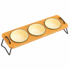 A three-bowl pet feeder made of light natural wood with black metal legs and handles, holding three pale yellow bowls with green rims, shown on a white background.