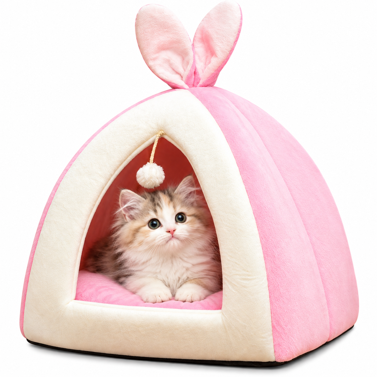 A fluffy kitten sits inside a pink and cream bunny house pet bed with upright bunny ears on top, photographed on a clean white background.